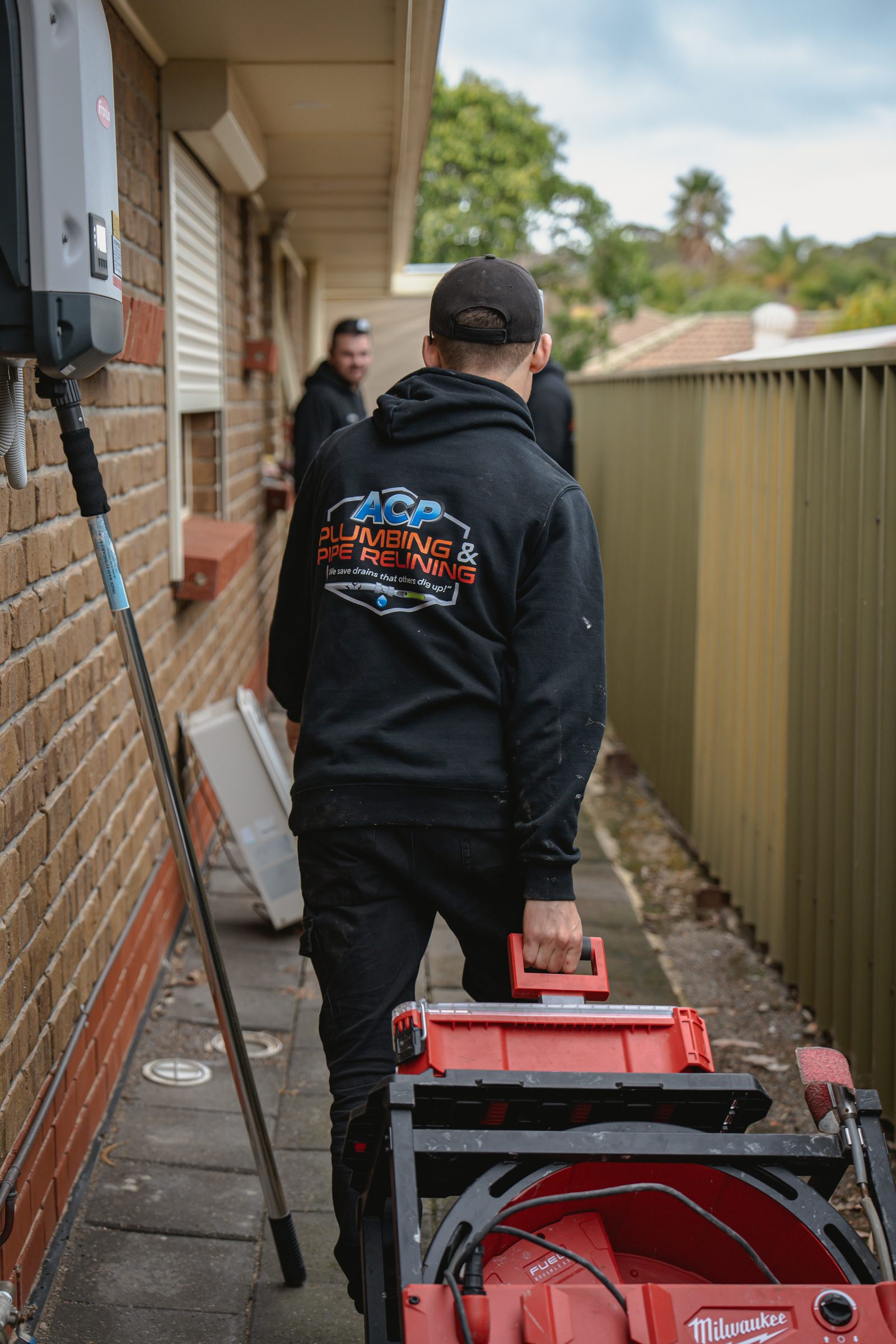 ACP plumber working along the side of a house